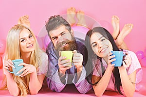 Lovers drinking coffee in bed. Lovers in bed concept. Man and women, friends on smiling faces lay, pink background. Man