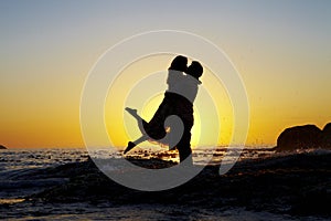 Lovers embrace silhouetted by a sunset