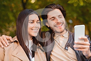 Lovers enjoying time together, taking selfie while walking by forest