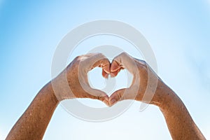 Lovers gesturing with heart sign on blurred blue background