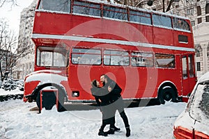 Lovers guy and girl kiss on the background of a red bus