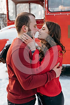 Lovers guy and girl kiss on the background of a red bus