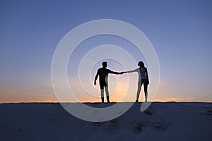 Lovers hold each other arms and swirl on sandy hill in desert on