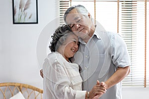 Lovers in a living room. Beautiful Asian senior couple smiling are enjoying spending time together while dancing. Senior family