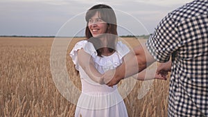 Lovers man and woman travel in field holding hands. Follow me, a young happy couple running along the golden wheat field