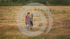 Lovers man and woman travel in the field holding hands. Follow me, a young happy couple running along golden wheat field