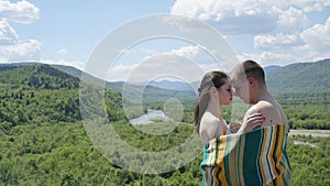 Lovers. Naked couple embracing covered by blanket. Guy embraces girl on green mountains background.