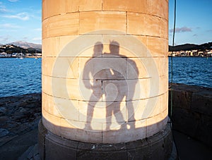 Lovers play with their shadows on  Lighthouse wall