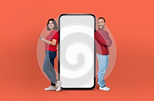 Lovers Presenting a Blank Smartphone Screen on Orange Background