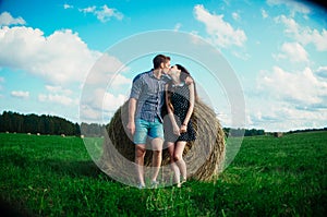 Lovers resting in a field near haystacks