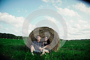 Lovers resting in a field near haystacks