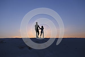 Lovers run towards each other and swirl on sandy hill in desert