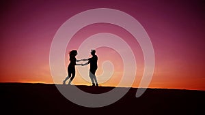 Lovers run towards each other and swirl on sandy hill in desert