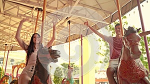 Lovers sitting in a carousel in an amusement park. Couples are having fun, playing like children.