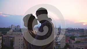 Lovers tenderly kissing spending romantic date on roof of multistory building