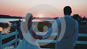 Lovers walk down the pier into the sunset and gentle kiss. Cool footage. The camera is in motion. Amazing lighting.