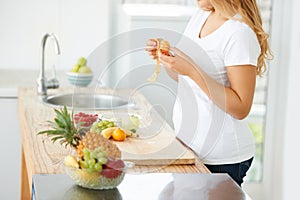 She loves citrus fruit. Curvaceous young woman peeling fruit in her kitchen.