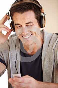 He loves his tunes. A handsome young man listen to music through his headphones.