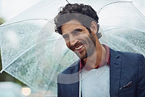 He loves the rain. Cropped shot of a handsome young businessman on his morning commute in the rain.