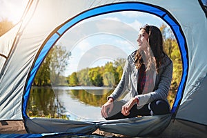 She loves roughing it. Full length shot of an attractive young woman sitting at her campsite.