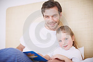 She loves storytime. A devoted father reading his young daughter a bedtime story.