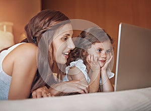 She loves watching her favourite cartoons with Mom. a mother and her little daughter using a laptop together at home.