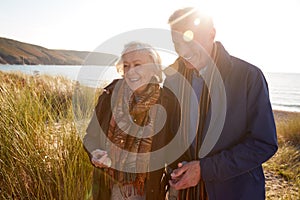 Loving Active Senior Couple Arm In Arm Walking Through Sand Dunes