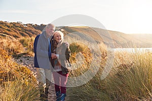 Loving Active Senior Couple Hugging As They Walk Through Sand Dunes