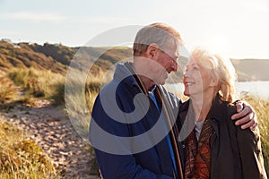 Loving Active Senior Couple Hugging As They Walk Through Sand Dunes