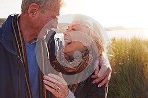 Loving Active Senior Couple Hugging As They Walk Through Sand Dunes