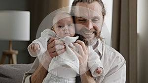 Loving adult bearded father holding baby newborn caring dad playing with little daughter son child jumping laughing man