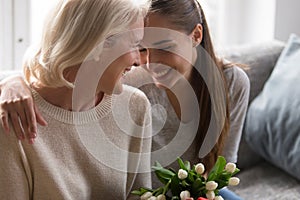 Loving adult daughter greeting mom with flowers