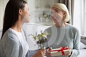 Loving adult daughter greeting senior mom with birthday