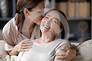 Loving adult daughter kiss senior mother relaxing together