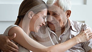 Loving adult daughter and older father touching foreheads, hugging