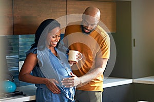 Loving African American Husband With Pregnant Wife At Home In Kitchen Together