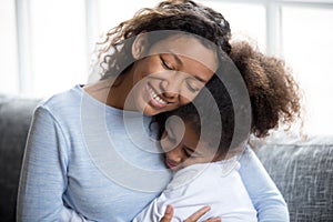 Loving African American mother embracing with daughter