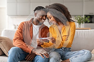 Loving African Man And Woman Holding Positive Pregnancy Test Indoor