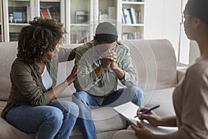 Loving african woman comforting her husband while having family therapy