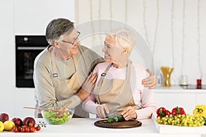 Loving Aged Husband Hugging Wife While Making Dinner In Kitchen