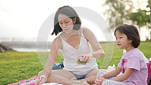 Loving asian chinese mother and daughter having picnic by the beach preparing food