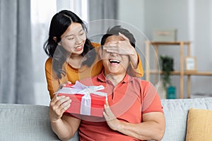 Loving asian woman making surprise for her boyfriend, giving present