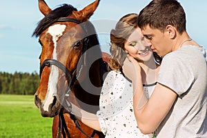 Loving beautiful couple of guys and girls in the field walk on horses