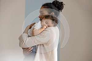 Loving biracial mom embrace little baby infant