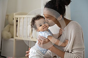 Loving biracial mom hug and kiss little baby