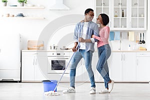 Loving black couple cleaning kitchen together, full length photo