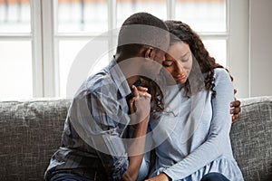 Loving black couple hug on couch making peace after fight