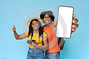 Loving black couple travelling together, showing mobile phone