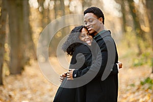 Loving black couple walking in park and enjoying autumn day