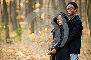 Loving black couple walking in park and enjoying autumn day